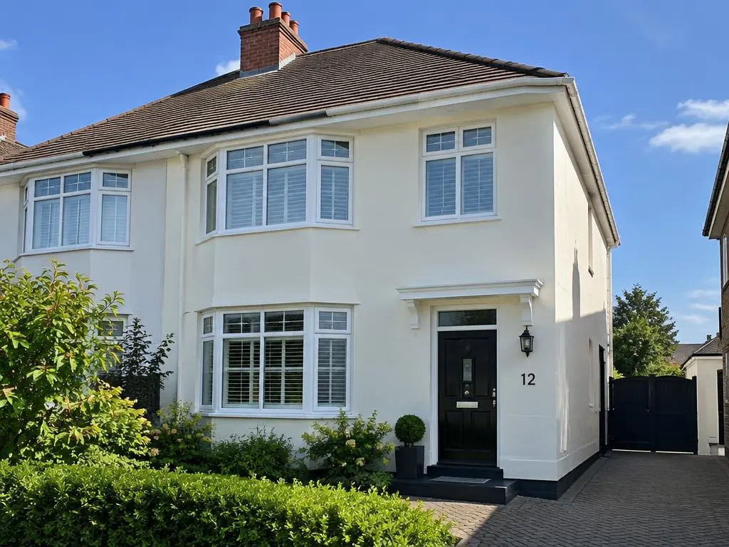 Semi-detached house with clean cream render, white bay windows and a black front door