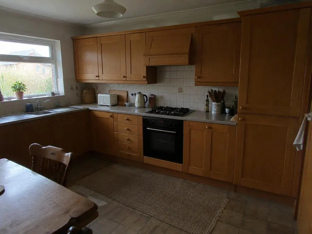 Kitchen with light oak shaker-style cabinets, grey worktops and tiled splashback