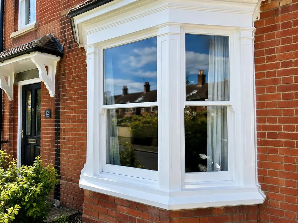 Bay sash window with smooth white paintwork on a red brick house